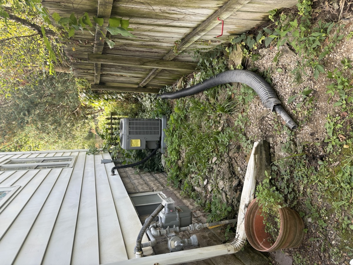 Overgrown drainage area before cleanup and gravel bed installation in Eastern Iowa